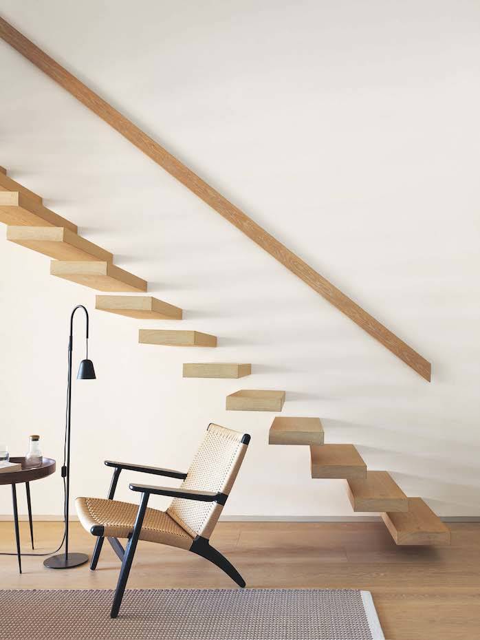 Escaleras, acceso a segunda planta Casa Da Rocha. En la suite principal, un rincón de lectura equipado con la lámpara de pie de Chaplin de Formagenda, la butaca CH25, diseño de Hans J. Wegner para Carl Hansen y la mesita auxiliar Bowl, diseño de Ayush Kastiwal, para la firma danesa Mater.
