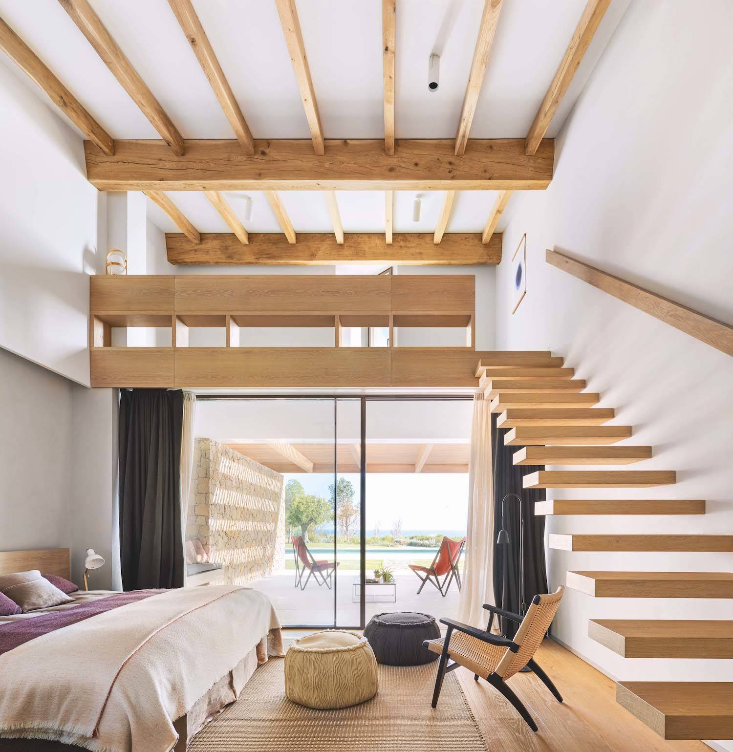 Habitación y planta de arriba de Casa Da Rocha. La suite principal conecta a través de una escalera de peldaños volados con un altillo desde el que se obtienen magníficas vistas de la costa del Algarve. La alfombra es el modelo Duetto 3, de Hanna Korvela. La ropa de cama es de Teixidors, en Matéria.