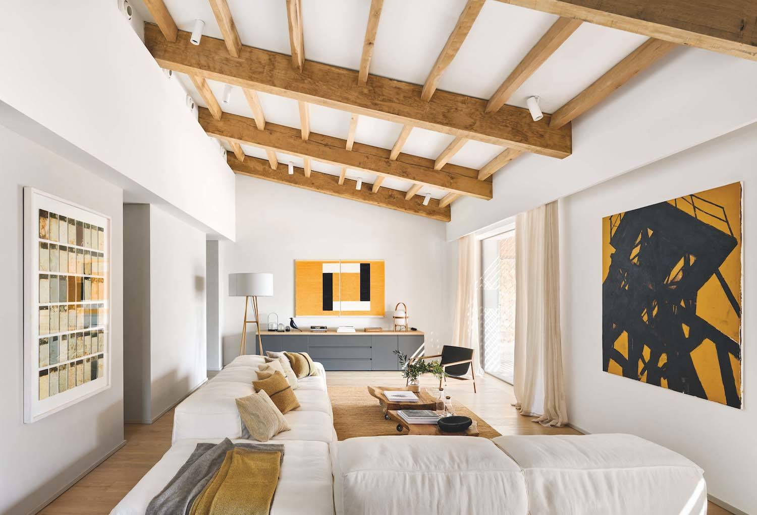 Vista general del salón de la Casa Da Rocha. La mesa de centro se ha realizado con troncos de olivo macizo, un gesto que reafirma la conexión natural de la casa. Butaca Sdraio, de Piero Lissoni para Living Divaní. Al fondo, sobre la mesa de comedor, dos lámparas de suspensión Spokes 2, diseño de García Cumini para Foscarini.