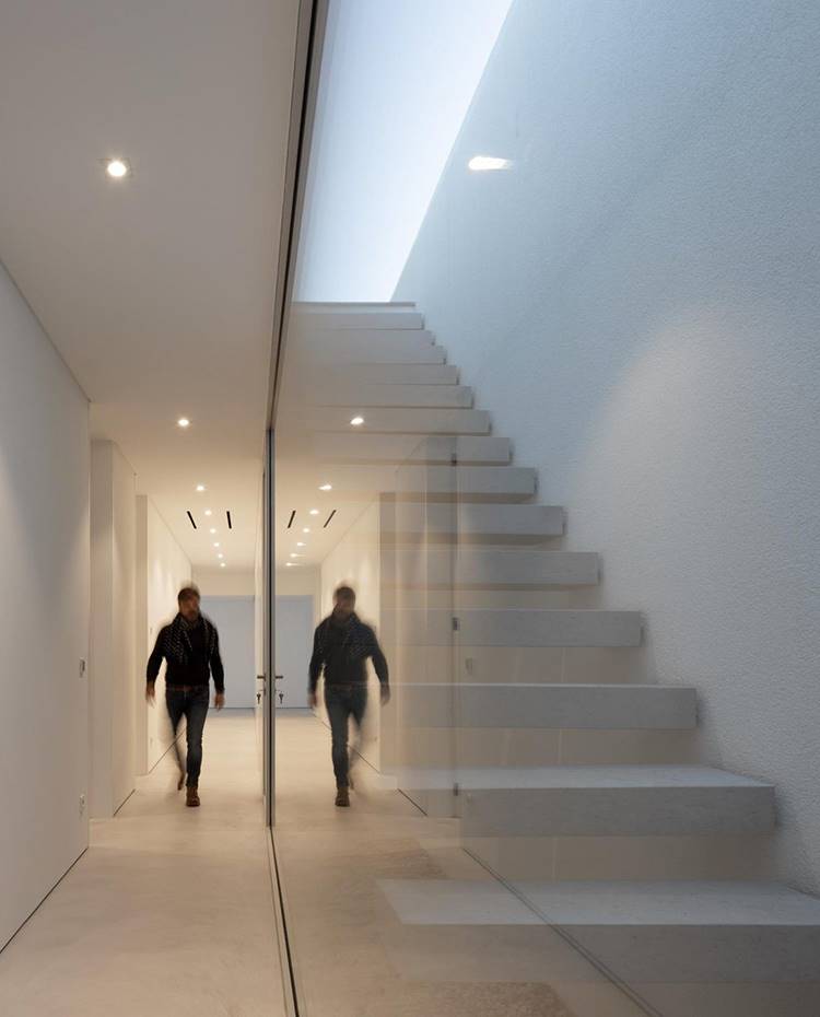 Escaleras voladas entre plantas, cerramiento cristal transparente, zonas de paso en blanco. La pureza de líneas y el aspecto níveo característicos del exterior del proyecto tienen su continuación en los interiores de la vivienda. Los espacios diáfanos, de estética minimalista, actúan como lienzos en blanco donde se impone la luz natural y la sencillez de formas. 