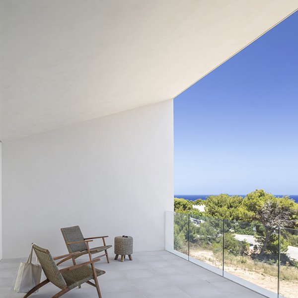 Terraza cubierta de hormigón con butacas de fibra y madera, puf de fibra y madera, vistas exterior islas