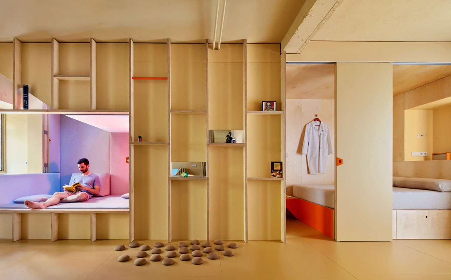 Vista frontal dos ambientes, chill out a la izquierda y dormitorio a la derecha, con puerta corredera y todo hecho a medida de madera