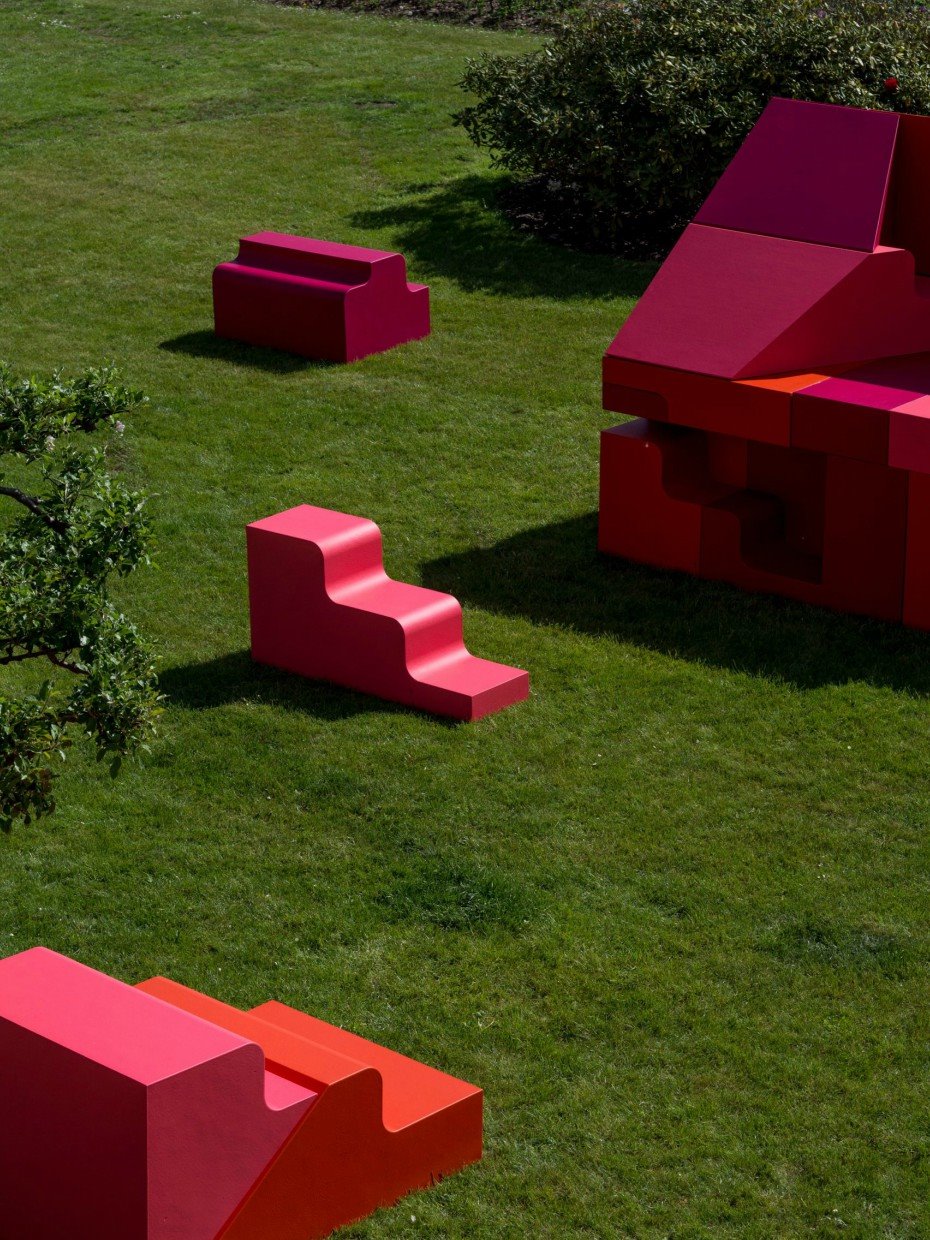Los bloques de tonos rosas y rojos se combinan entre ellos para formar asientos, gradas o una vivienda.