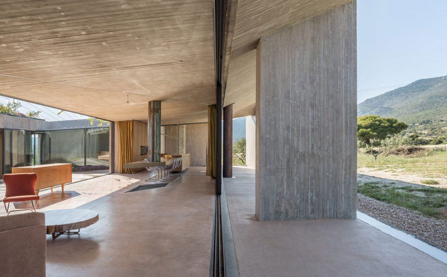 Salón-comedor-cocina, marco de cerramiento, estructura de hormigón, mesa y sillas transparentes de comedor, vista exterior campo