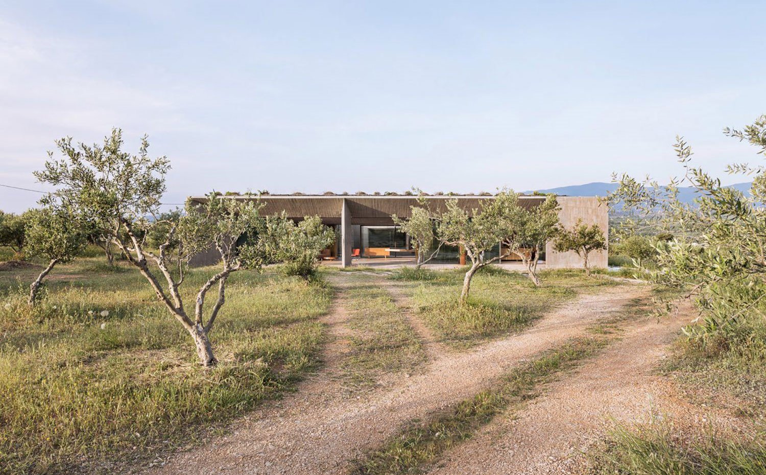 Vista acceso a vivienda, camino de tierra, árboles junto al camino, fachada exterior apaisada