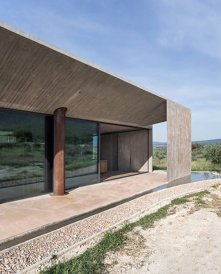 Zona exterior junto a cocina, estructura fachada de hormigón, cerramientos cristal transparente, columna de acero corten