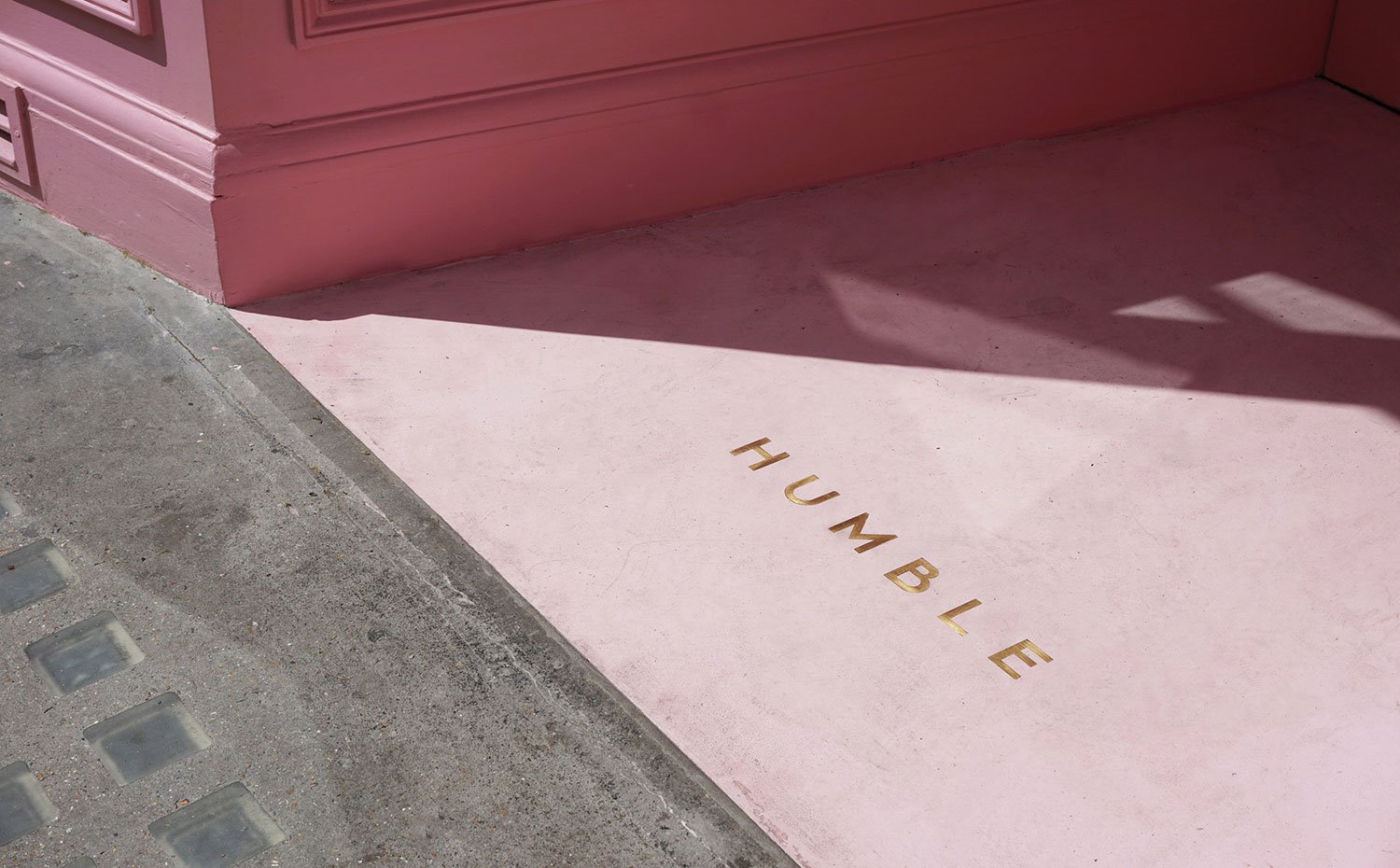 Detalle del suelo del nombre del establecimiento en dorado sobre entrada en rosa
