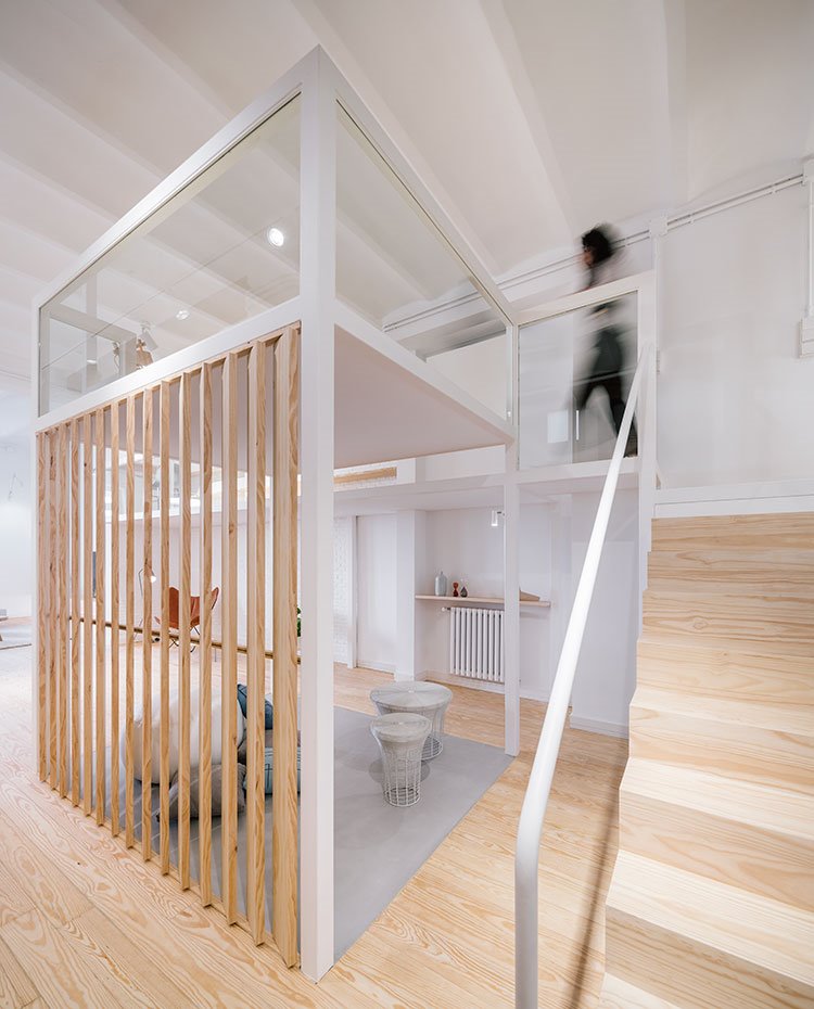 Escaleras-de-madera-hacia-piso-superior,-barandilla-tubular-blanca,-pavimento-madera-cubículo-con-lado-alistonado-y-suelo-de-hormigón.