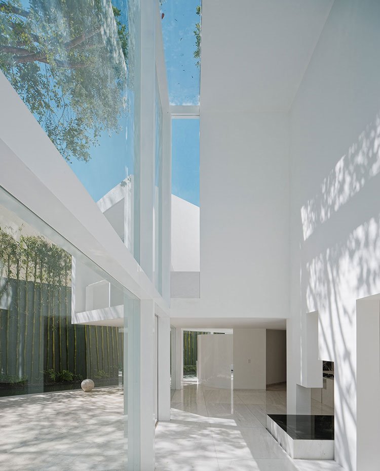 Estructura blanca, grandes aperturas a exterior, altos techos, paredes blancas, cerramientos de cristal, exterior con árboles