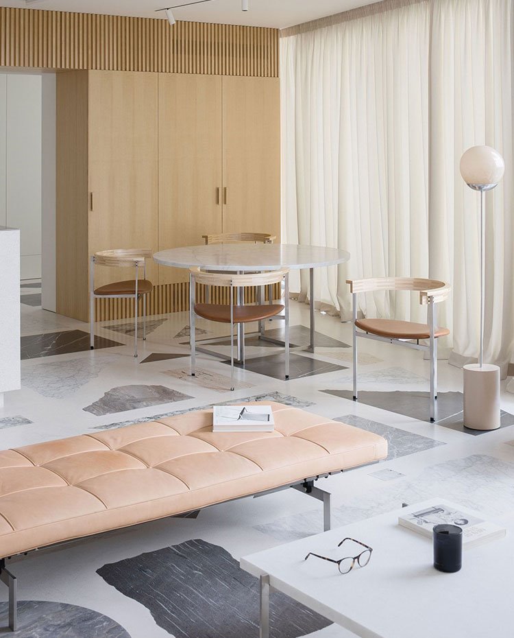 Mesa de centro con gafas, asiento bajo color crema, suelo de mármol, mesa de comedor circular, sillas semicirculares, armarios de madera