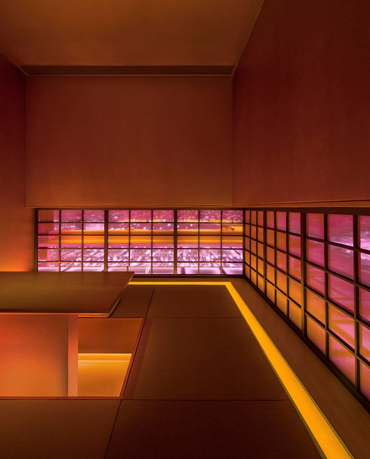 Interior sala privada en amarillo con ventanas horizontales, mesa cuadrada con asientos de obra a su alrededor