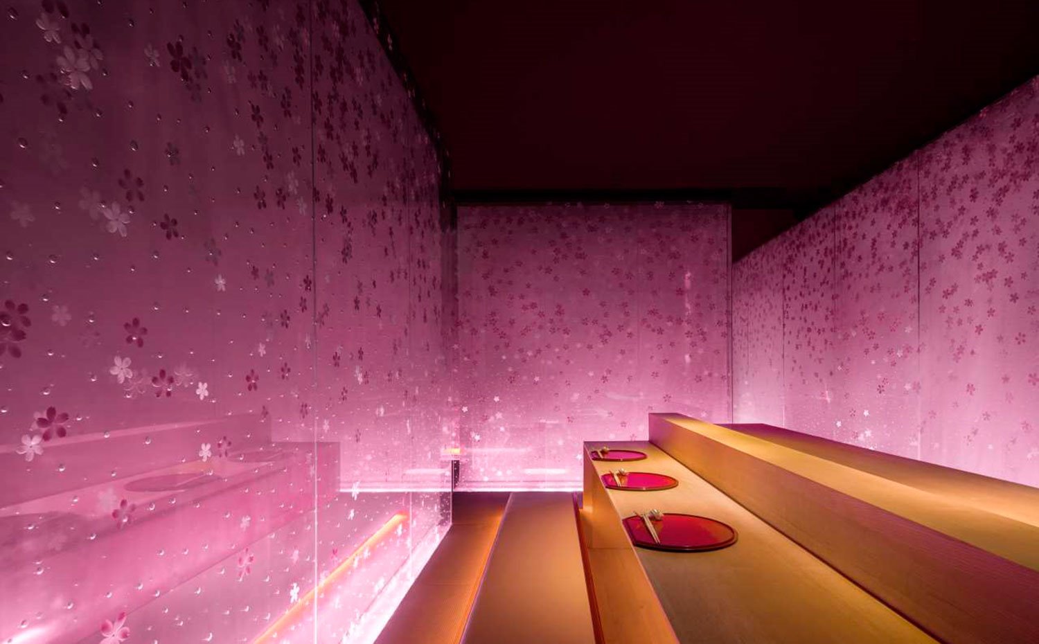 Mesas y bancadas en amarillo, vajilla en rojo, paneles con motivos en rosa