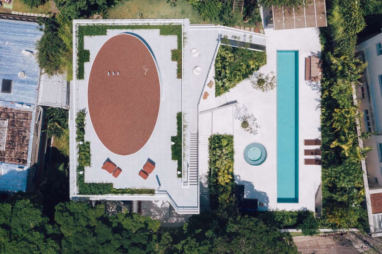 vista-cenital-vivienda-con-piscina-rectangular-junto-a-jacuzzi-y-terraza-azotea-vivienda-con-cubierta-ovalada. Objeto de varias ampliaciones y modificaciones arbitrarias, la vivienda ha vivido una renovación integral que le ha otorgado una coherencia estética y funcional, respetando la identidad original de la casa.