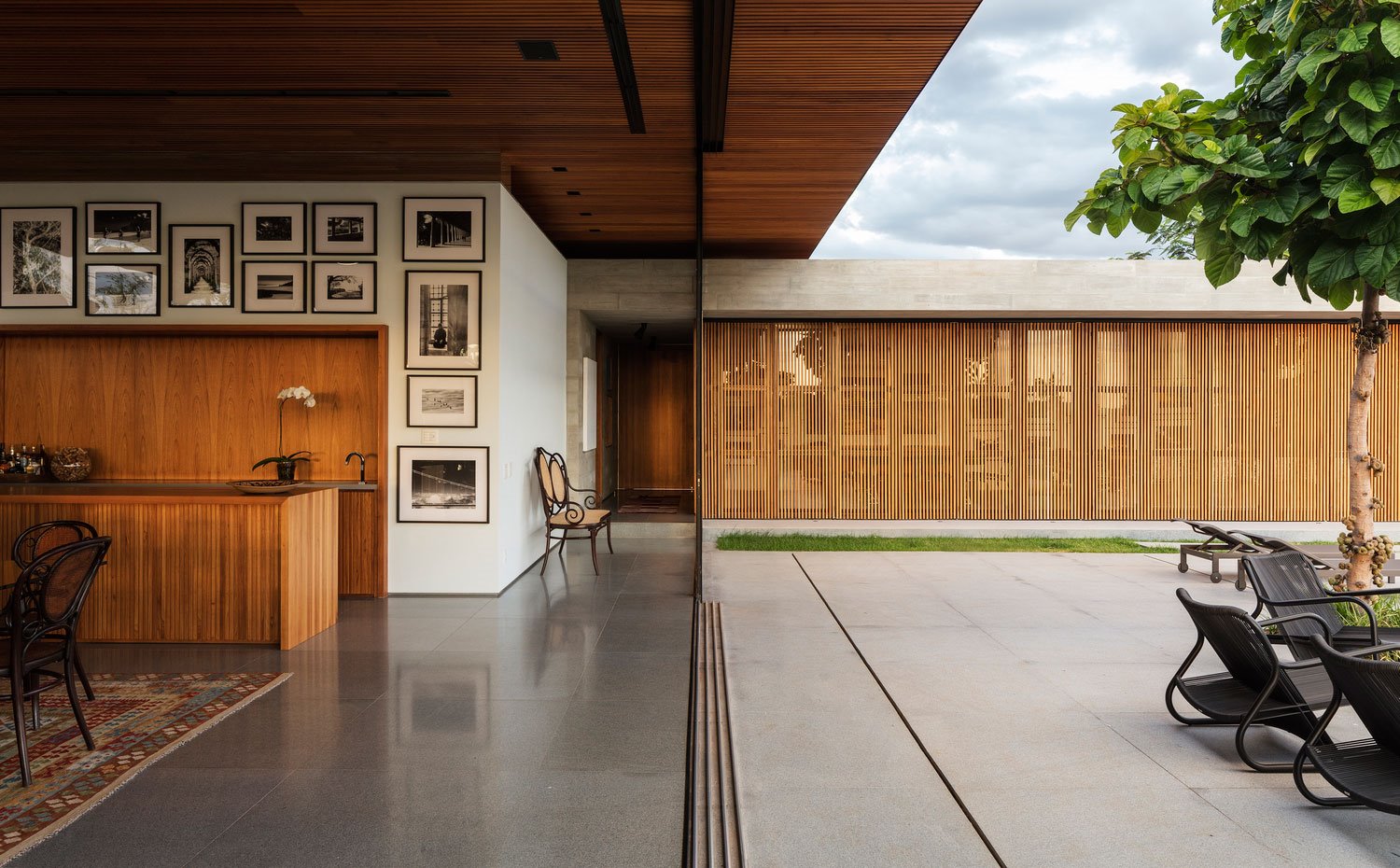 Cocina abierta a comedor, apertura a terraza exterior con cerramiento de cristal y alistonado de madera, fotos en mared, alfombra en comedor, sillas de madera estilo clásico
