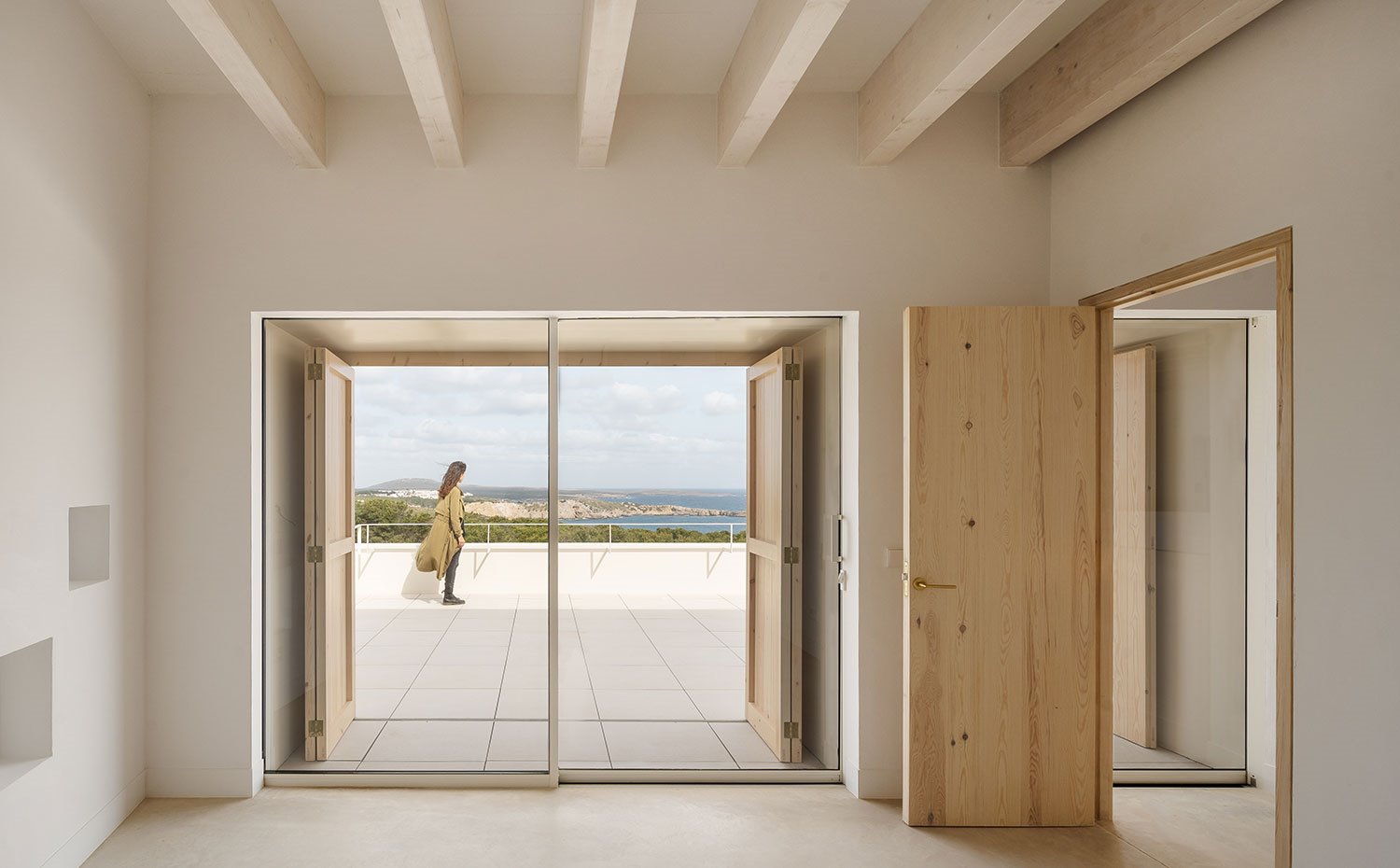 Interior habitación con cerramiento de cristal, puerta de madera y terraza exterior