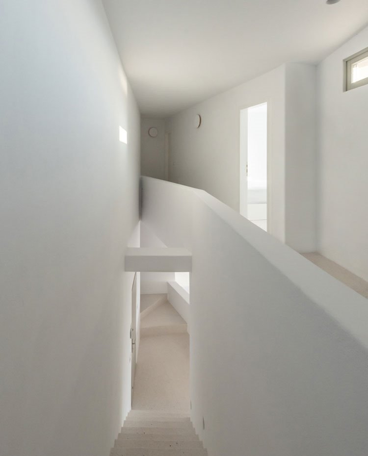 Zona de paso entre niveles con un primer tramo de escaleras y un segundo a modo de rampa, todo en blacno