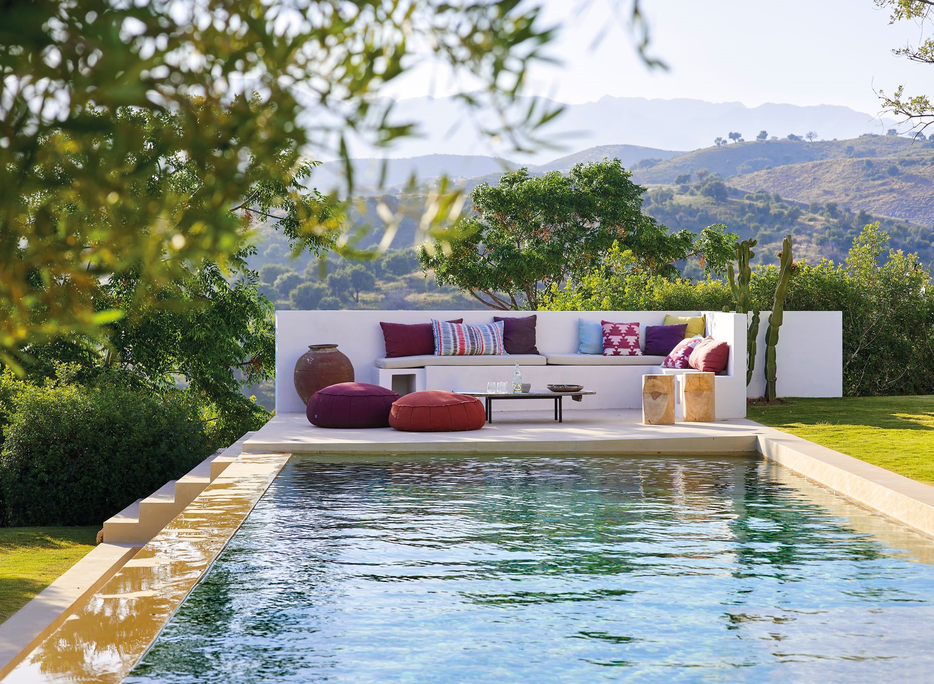 sofá con cojines estampados de Nezha Kanouini , mesa de madera, de DM Interiors, pufs modelo Float de Francesco Rota para Paola Lenti,