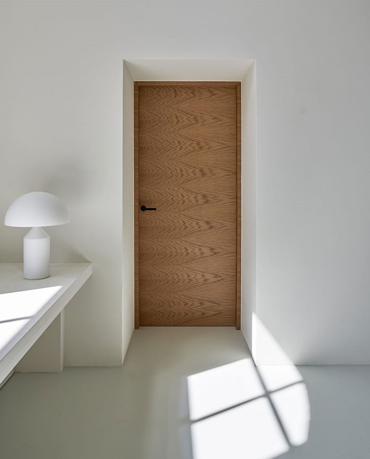 Puerta de acceso en madera natural, estante de obra con lámpara de sobremesa en blanco
