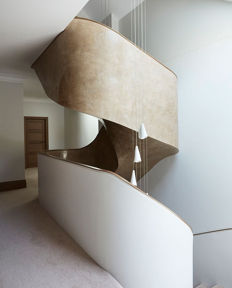 Tramo de escalera envolvente, pavimento enmoquetado, luminaria suspendida en hueco escalera