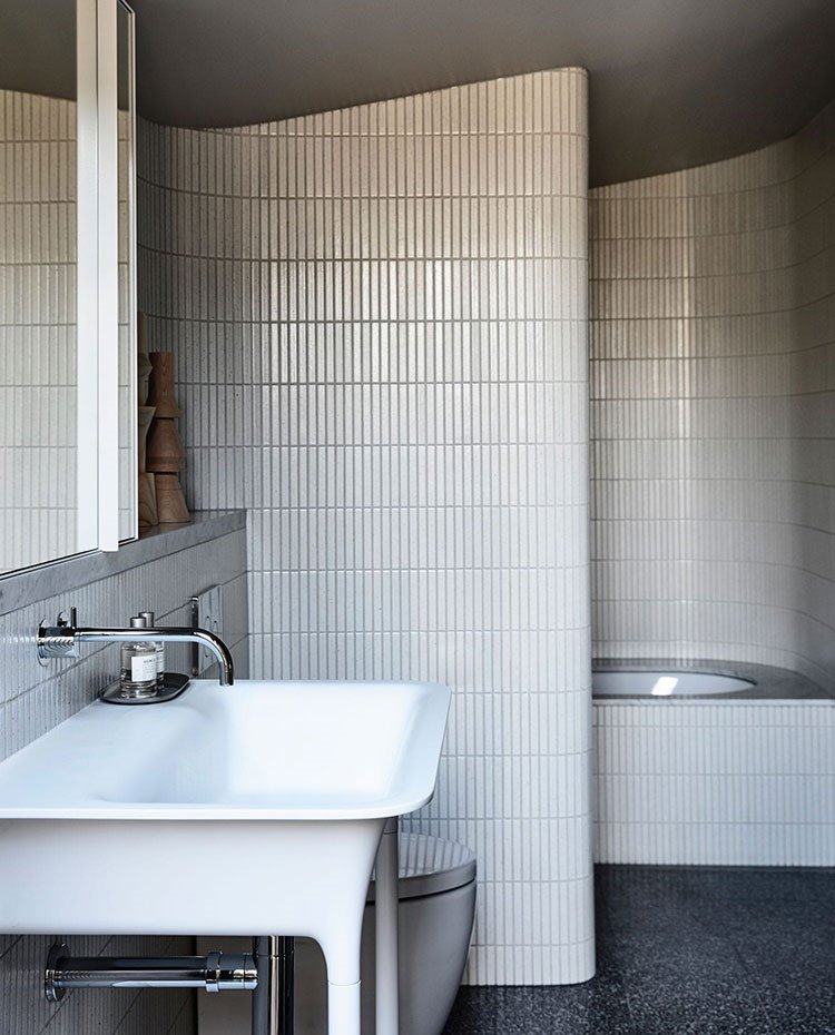 Cuarto de baño revestido con baldosas alistonadas, encimera frente a mueble con armario, lavabo y bañera