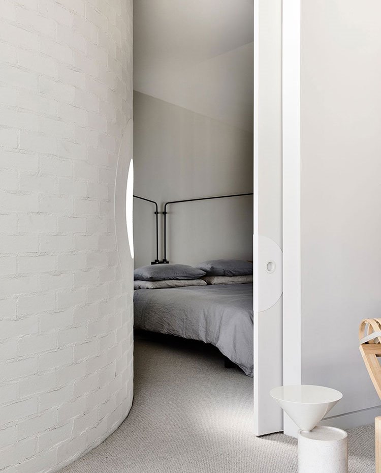 Entrada dormitorio con pared curva, cerramiento corredero, suelo emmoquetado, estructura cabecero de líneas sutiles