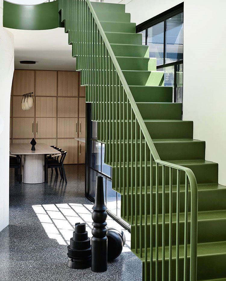 Escaleras metalizadas en verde, piezas decorativas bajo escalera en negro, mesa de comedor cccina con sobre de madera