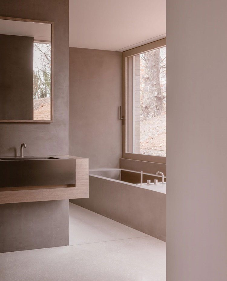 Cuarto de baño con lavamanos de cristal y madera, ballera de obra y grifería encastrada, gran ventanal a exterior