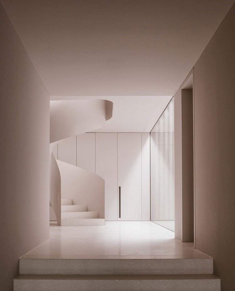 Escaleras de caracol hacia piso superior, frente de armarios en blanco, suelo blanco, cerramiento acristalado