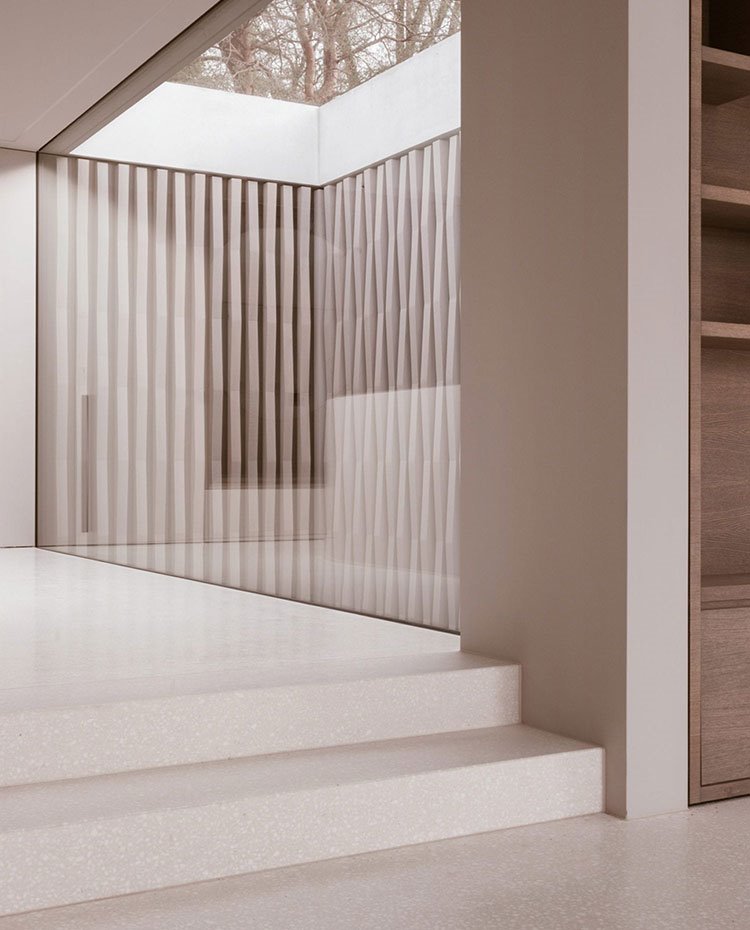 Escaleras hacia zona de paso con patio interior acristalado, librería de madera