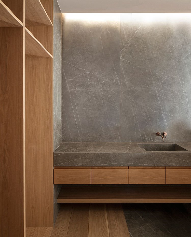 Cuarto-de-baño-con-suelo-de-madera,-encimera-y-revestimiento-de-granito,-mueble-bajolavabo-suspendido-con-balda-inferior-de-madera