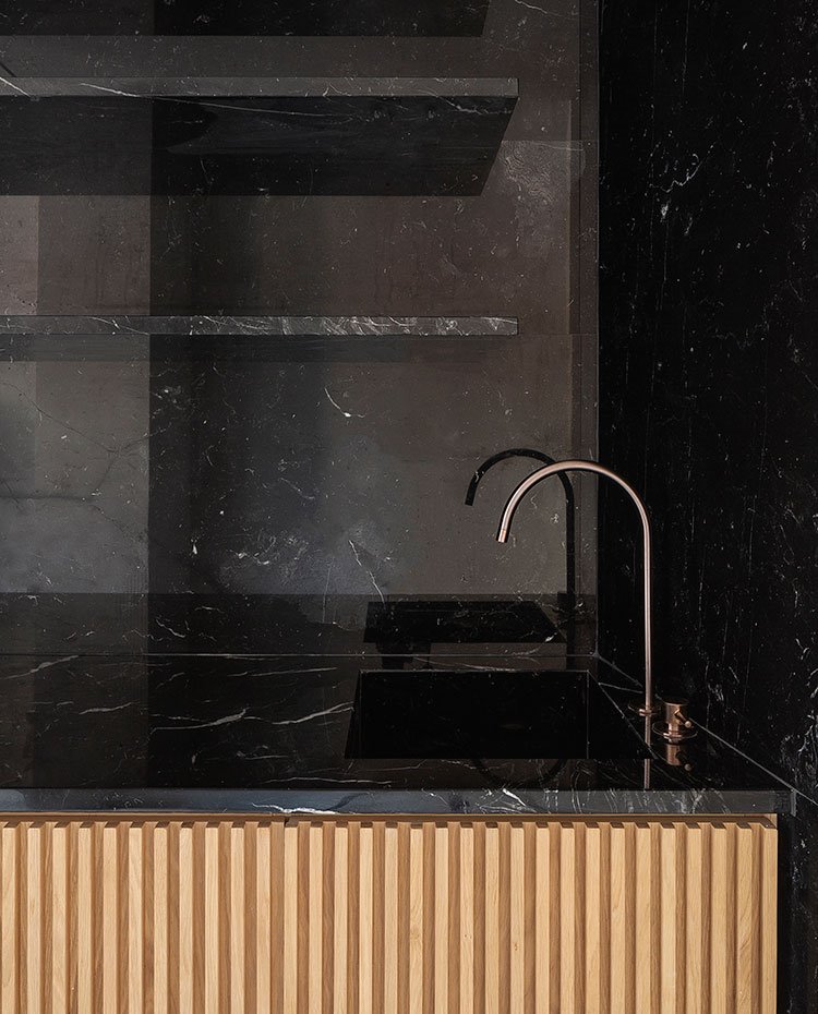 Zona-de-aguas-de-cocina,-revestimiento-en-granito-negro-con-frentes-de-armario-en-relieve-de-madera-natural