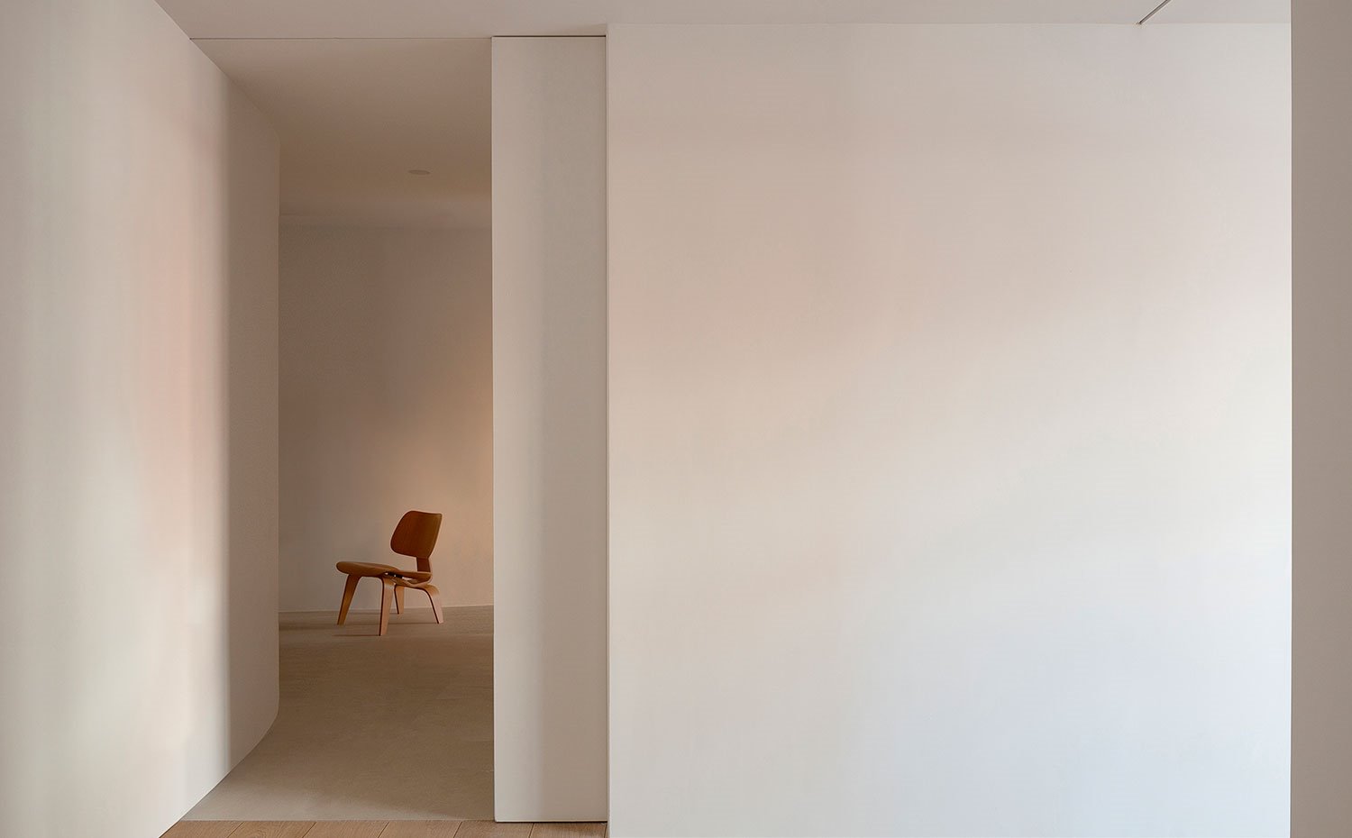 Zona-de-paso-con-acceso-a-dormitorio-a-través-de-puerta-corredera,-suelo-de-madera-y-piedra,-butaca-de-madera