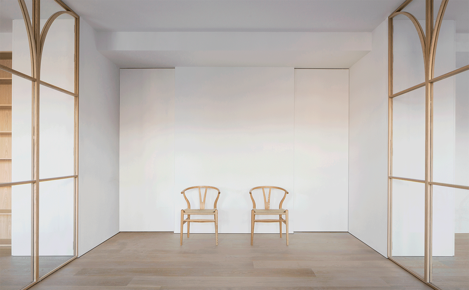Zona-de-paso-con-dos-sillas-de-madera-y-puertas-correderas-con-cerramientos-de-cristal-y-perfil-de-madera-a-cada-lado