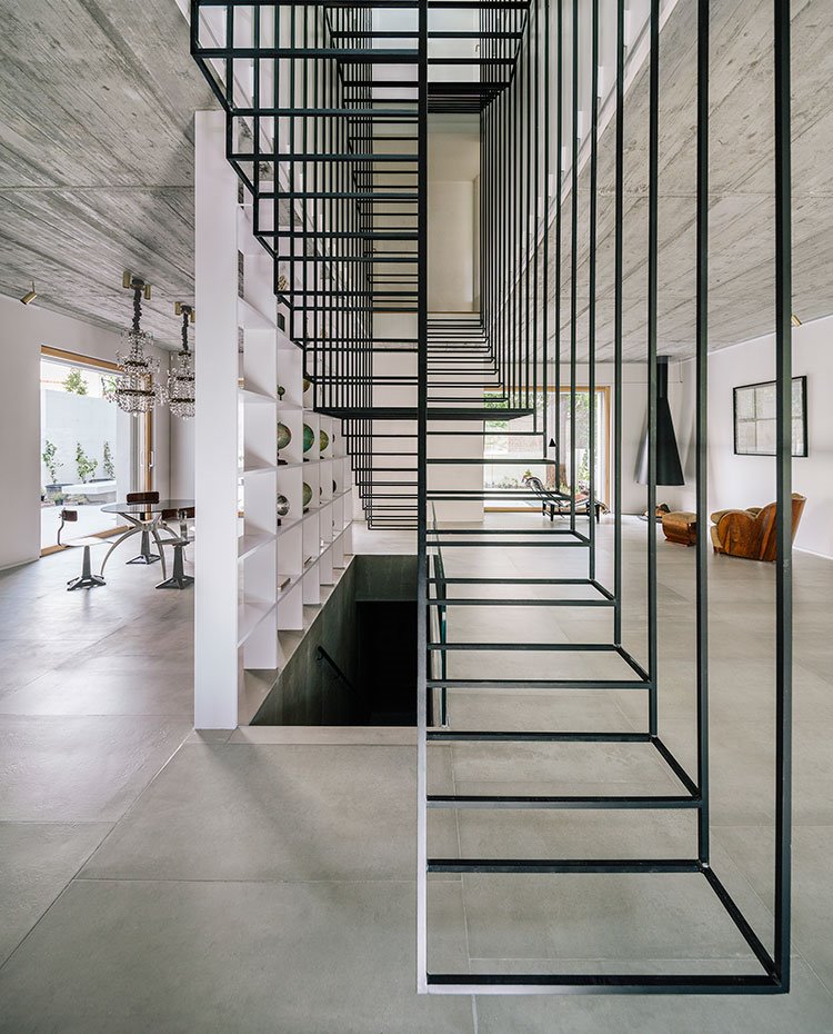 Estructura suspendida dibujando los diferentes peldaños, suelo porcelánico, librería blanca, comedor y sala de estar