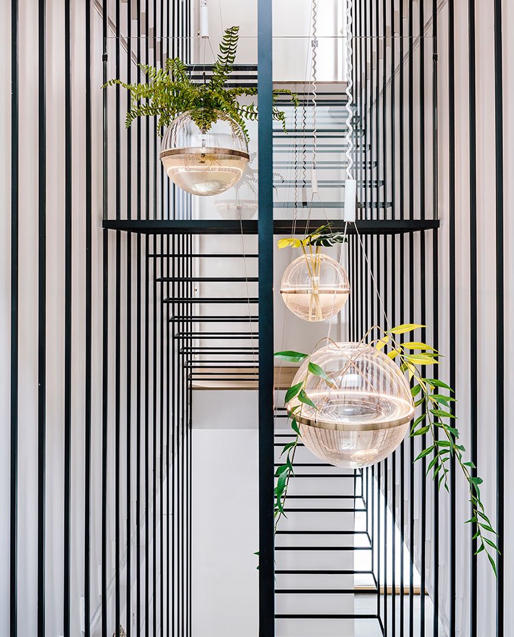 Jardineras esféricas con agua suspendidas entre la estructura volumétrica cromada en negro 