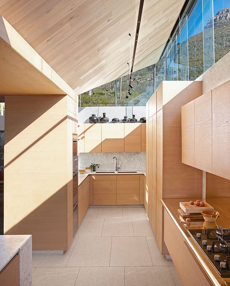 Cocina con mobiliario en madera abierta al salón, cerramientos superiores en cristal