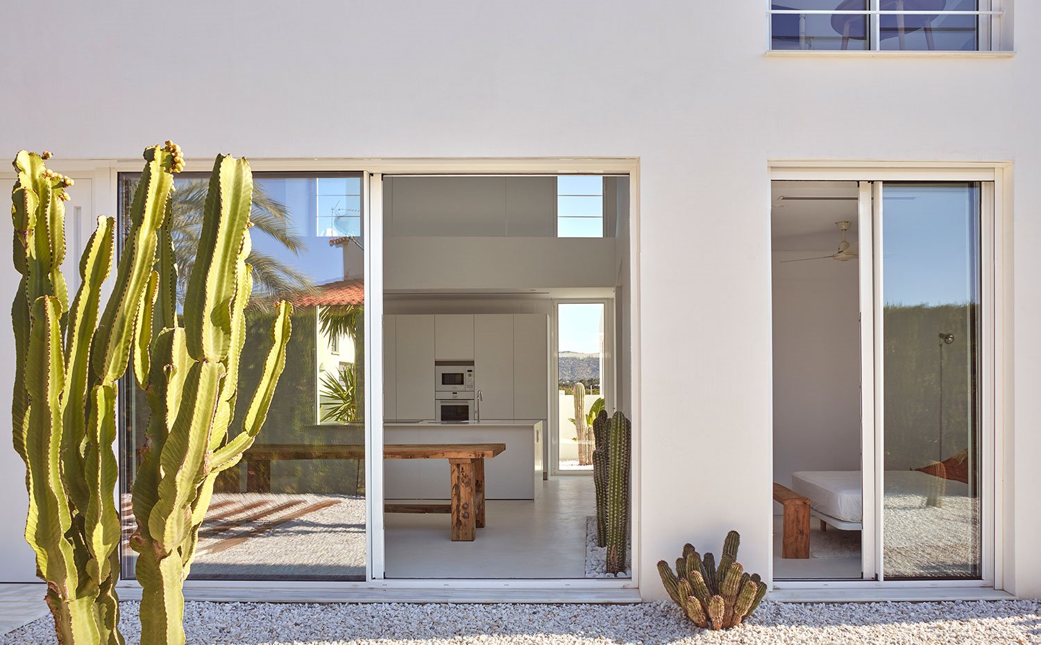 Cerramientos de crisal a exterior, suelo de graba, cáctus, cocina junto a dormitorio