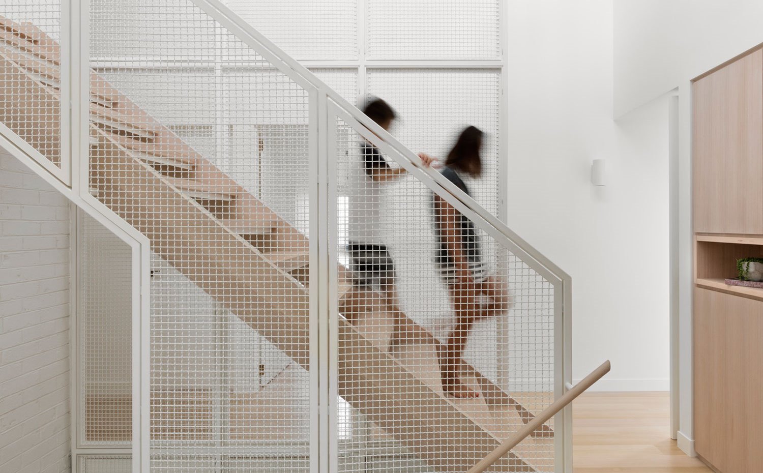 Escaleras entre niveles con estructura divisoria cromada blanca con escaleras y pasamanos de madera 