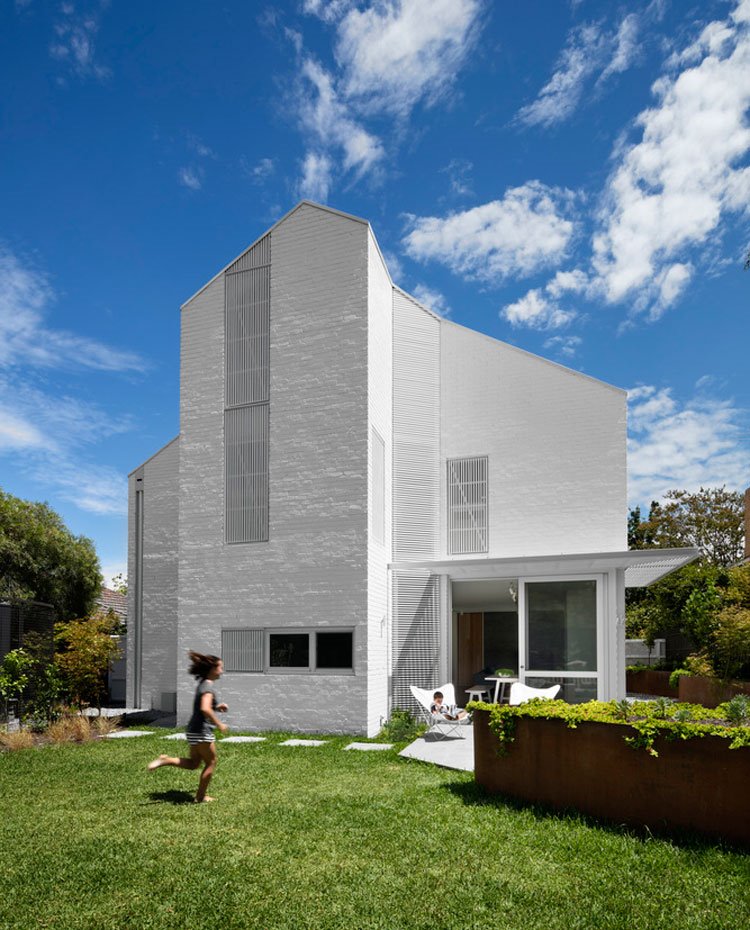 Fachada exterior de la vivienda con jardín alrededor, patio con porche