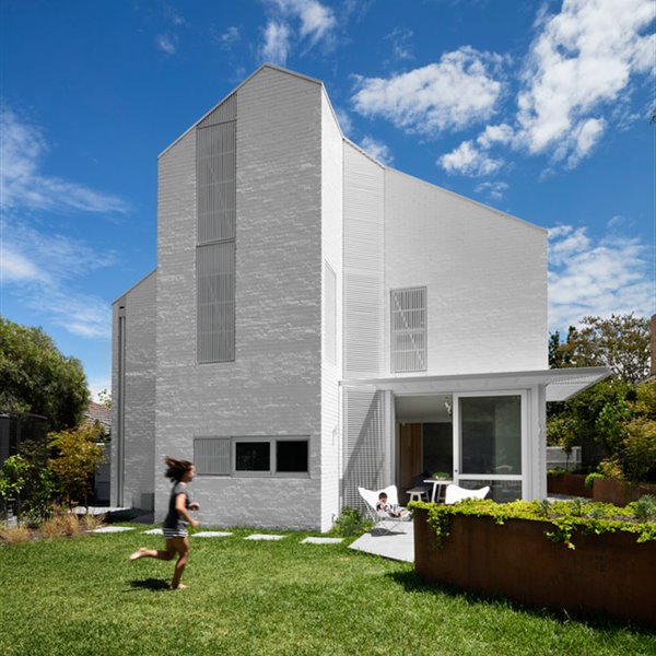 Fachada exterior de la vivienda con jardín alrededor, patio con porche