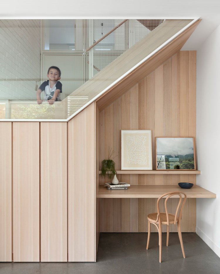 Zona de trabajo bajo hueco escalera, todo revestido de madera, con mesa y estante a juego y silla de madera