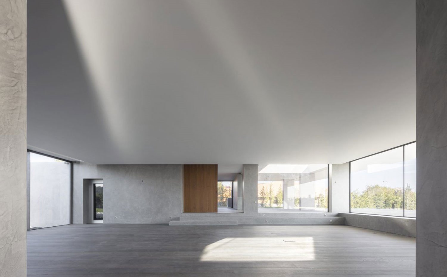 Interior diáfano con paramentos de hormigon y cristal, puertas de madera