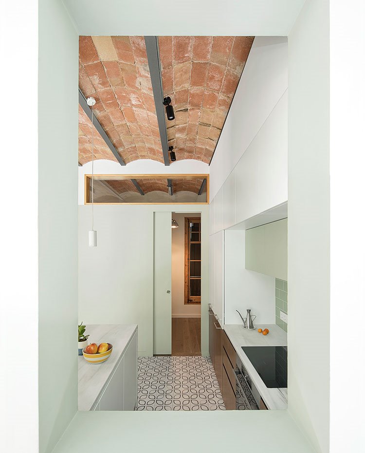 Apertura de cocina a comedor, con vista de zona de trabajo y puerta corredera, techo con bóveda catalana
