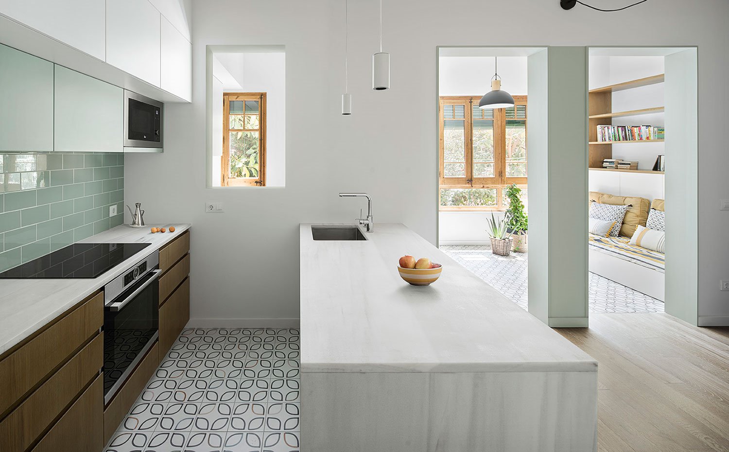 Cocina con revestimiento en verde, suelo baldosa, península con encimera de mármol, apertura a salón y comedor
