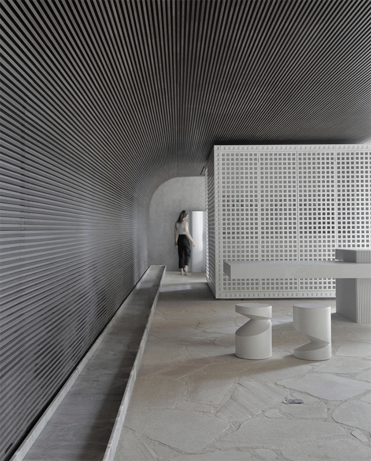 Zona-de-paso-con-taburetes-en-blanco,-paredes-alistonadas-con-cantos-curvos,-módulo-blanco-perforado,-mueble-con-encimera-volada