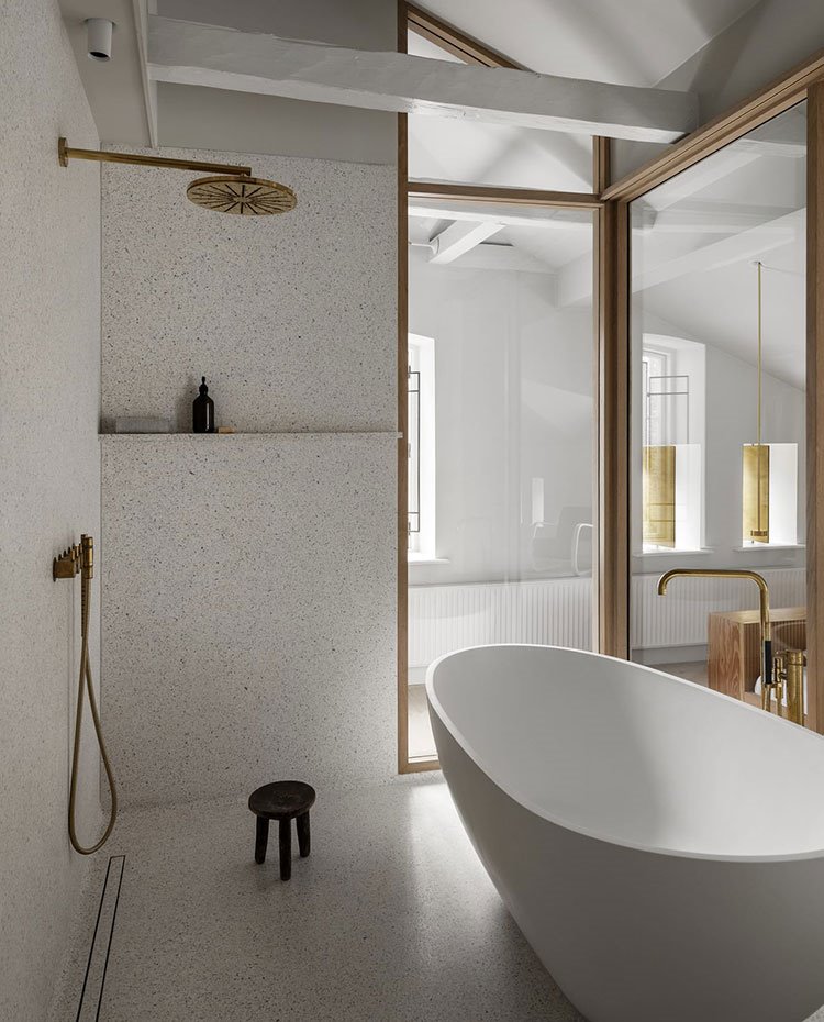 Cuarto de baño con cerramiento de cristal transparente, ducha de obra con plato de ducha y desague incorporado, estante para jabón y taburete, bañera exenta blanca