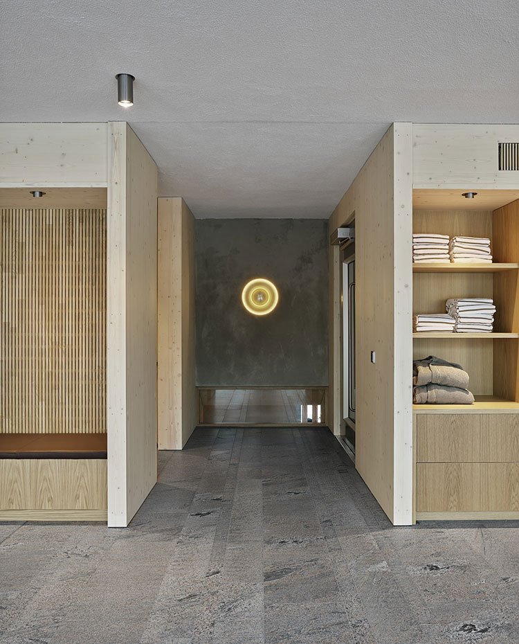 Frente de acceso al spa con equipamiento a medida de madera, bancada y estantes para toallas 
