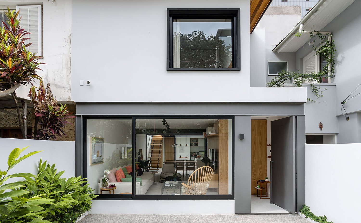 Exterior fachada en blanco con grandes aperturas y puerta de acceso abierta 