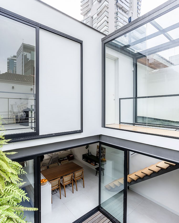 Estructura desde segunda planta en blanco con vigas y perfilería de hierro en gris, cerramientos en cristal transparente