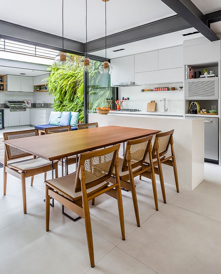 Mesa de comedor y sillas de madera, mobiliario de cocina en blanco, patio interior con barbacoa 